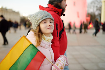 Father and daughter holding tricolor Lithuanian flag on Lithuanian Independence Day. Family celebrating national holiday.
