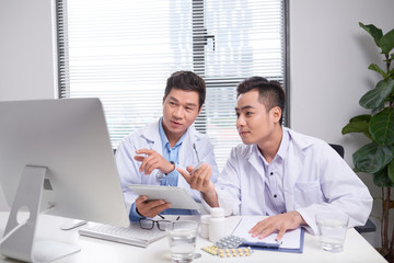 Obraz premium Two doctors holding and talking about patient on office