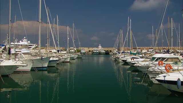 Wide low-angle still shot facing Le Nomade monument, of docked yachts lined at Marina Port, Vauban Antibes, France