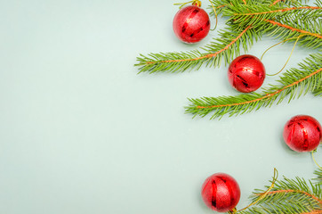 Christmas tree branches with red balls on a light blue background, copy space. Christmas background with copy space. view top