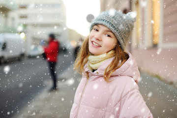 Adorable young girl having fun on beautiful winter day in a city. Cute child having a walk in winter town.