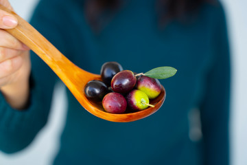 Fototapeta premium A woman handful of Mediterranean olives on a wooden spoon