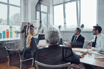 Modern businessman conducting presentation and analyzing data on the graph while having staff...