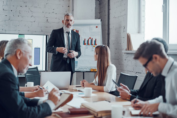 Mature businessman conducting presentation while working together with colleagues in the board room