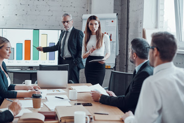 Successful business professionals presenting analytical report while working together with colleagues in the modern office