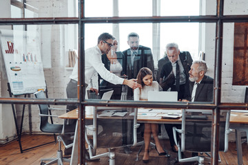 Professional business team analyzing sales using modern technologies while having staff meeting in the board room