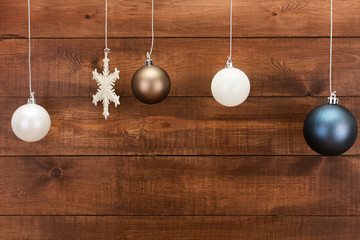 Christmas baubles hanging over wooden dark brown wall. New Year and Christmas background concept. Copy space, ball, snowflake