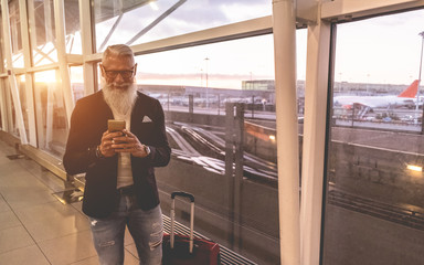 Senior trendy man using smartphone inside international airport - Soft focus on his face