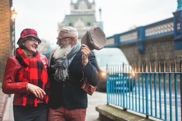 Happy senior couple walking in London near Tower Bridge - Mature tourists having fun discovering...