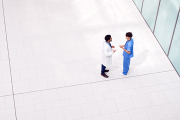 Overhead View Of Male Medical Staff Having Informal Meeting In Lobby Of Modern Hospital Building
