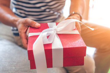 Man hands hold red gift box toward front. Valentines gift box. Season greeting.