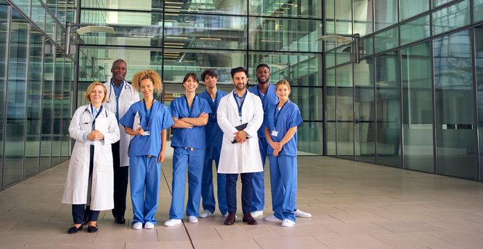Portrait Of Smiling Medical Team Standing In Modern Hospital Building