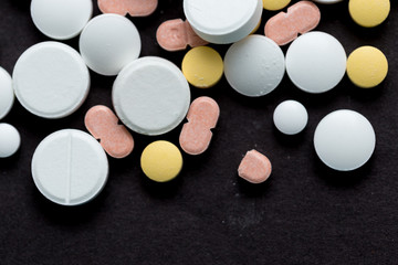 Colorful medical pills on a black background, for your text
