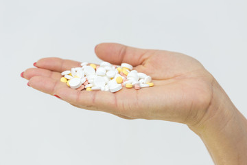 in the girl’s hand a lot of pills on a white background