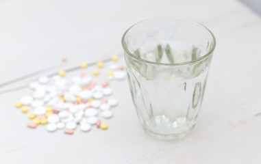 Colorful medical pills with a glass of water on the table, for your text