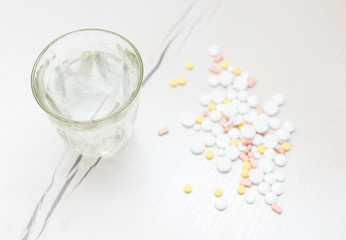 Colorful medical pills with a glass of water on the table, for your text