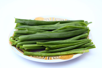 green onion on white background . onions which are green onions white plate with some smaller green onions sliced next to it on a kitchen table.
