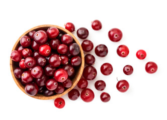 Cranberries in a wooden plate and scattered on a white background. The view of top.