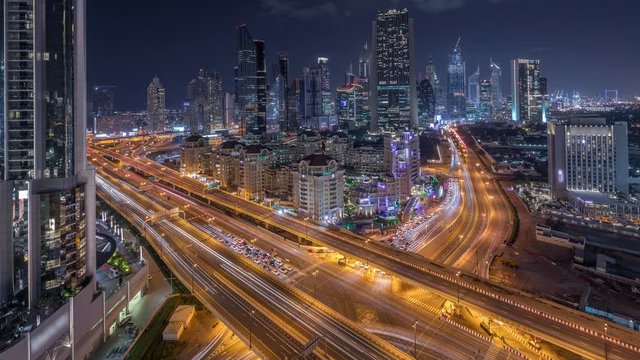 Skyline view of intersection traffic near Sheikh Zayed Road and DIFC day to night transition timelapse in Dubai, UAE. Illuminated skyscrapers in financial centre aerial view from above in downtown