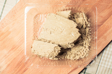 Large piece of fresh halva in transparent package on wooden board.