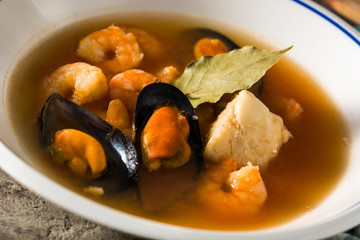 French bouillabaisse soup on wooden table. Close up