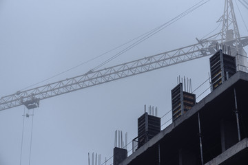 Construction crane in foggy weather on the construction of residential buildings.