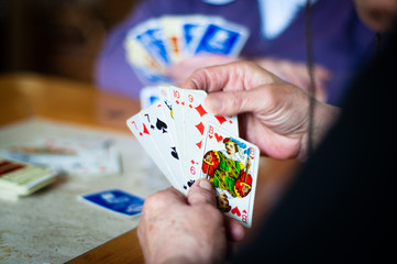 Elderly grandmother is playing cards. She is holding cards in her hand.