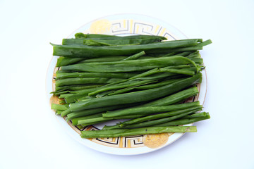 green onion on white background . onions which are green onions white plate with some smaller green onions sliced next to it on a kitchen table.