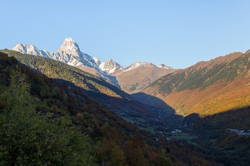 Panoramic  views of the mountains and Ushguli peak in the snow, visible in the distance, in the mountainous part of Georgia - Svaneti at sunset
