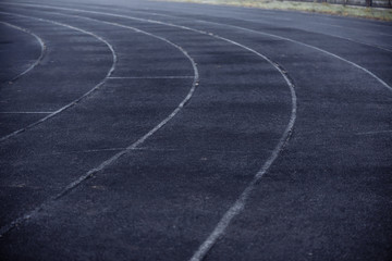 Running black rubber track at outdoor stadium in the fog