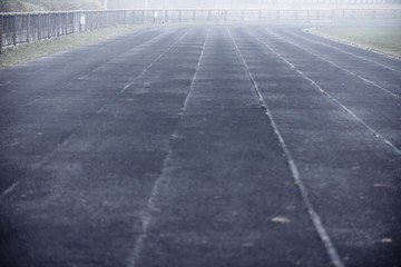 Fototapeta na wymiar Running black rubber track at outdoor stadium in the fog