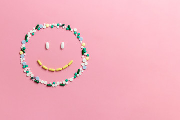 Composition of pills and capsules on a pink background in the form of a smile. Happy emotions. Psychological help. Copy space. View from above. Flat lay.