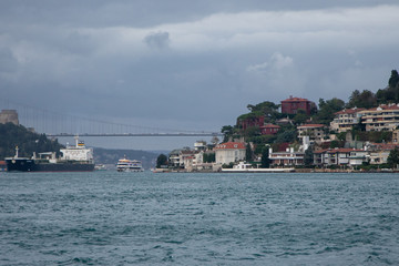 Fototapeta na wymiar View of a dry cargo ship, Bosphorus, Asian side and some houses in a sunny cloudy day in Istanbul.