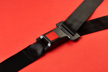 Fastened seat belt on red background with copy space, close-up