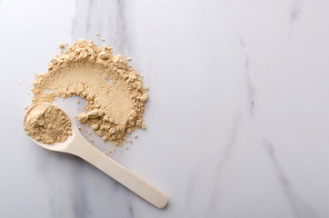 Top view of wooden spoon and smear of dried ginger powder on the kithcen table.Empty space for text
