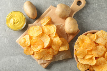 Potato chips. Beer snacks, sauce, potato on cutting board, on grey background, space for text. Top view