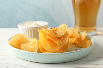 Potato chips and glass of beer. Beer snacks, sauce on white wooden background, space for text