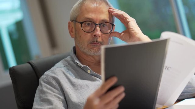 man reading a manuscript in his office