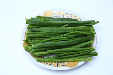 green onion on white background . onions which are green onions white plate with some smaller green...