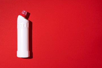 White plastic bottle of cleaning product, household chemicals or liquid laundry detergent on red background. Top view. Flat lay. Copy space. Detergent bottle