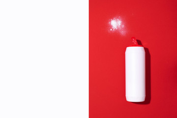 White plastic bottle of detergent powder or cleaning agent on red background. Copy space. Top view. Flat lay. Household chemicals concept
