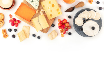 An assortment of cheeses, shot from the top on a white background with a place for text. Blue cheese, soft cheese and other sorts with fruit and nuts
