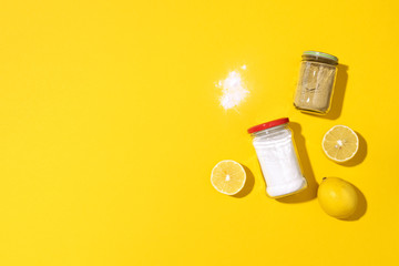 Eco-friendly natural cleaners. Baking soda, salt, lemon and mustard powder on yellow background....