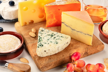 Cheese platter. Blue cheese, red Leicester, Brie, Emmental and others with wine and grapes on a white background
