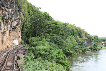 Scenery of railway beside the mountain and river with tropical forest.