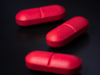 Three red pills on black background, Macro photography. background on the medical theme