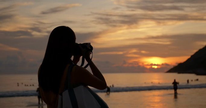 Woman take photo on camera at sunset on beach