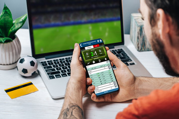Man making bets online using mobile application on his phone - 305721909