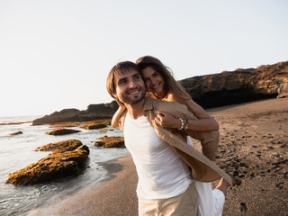Fototapeta na wymiar Attractive couple on vacation on the shore of the ocean at sunset time