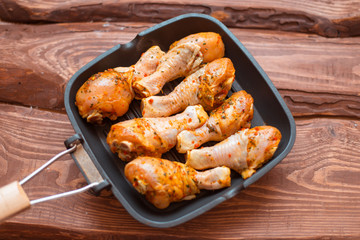 Raw chicken drumsticks in sauce and spices in a pan not a wooden background.